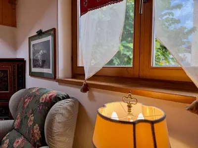 a room with a chair and a table and a window at L'Antico Fienile - Val di Fiemme in Daiano