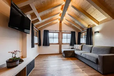 a living room with a couch and a flat screen tv at Ciasa Francësch in La Villa