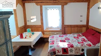 a bedroom with a bed and a table and a window at La Maison de Charlotte - Val di Fiemme in Ziano di Fiemme