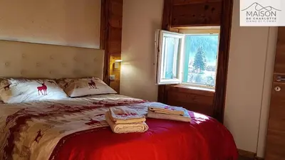 a bedroom with a red bed and a window at La Maison de Charlotte - Val di Fiemme in Ziano di Fiemme