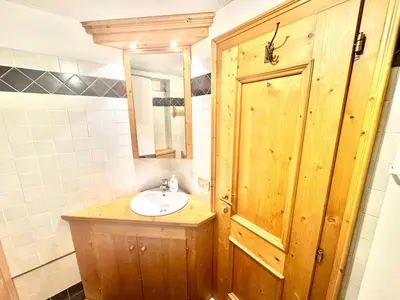 a bathroom with a sink and a wooden cabinet at Cozy Apartment - Alverà in Cortina dʼAmpezzo