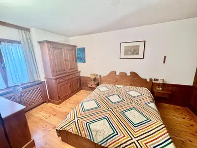 a bedroom with a bed and a wooden floor at Cozy Apartment - Alverà in Cortina dʼAmpezzo