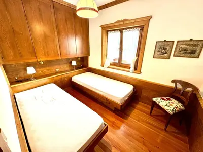 a room with two beds and a window and a chair at Ca Montagni - High-end apartment Verocai in Cortina dʼAmpezzo