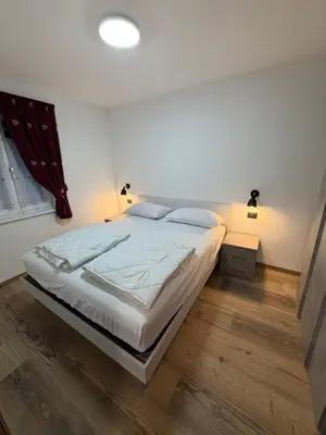 a bedroom with a bed with white sheets and pillows at Chalet La Viola in Alba di Canazei