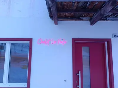 a red door on the side of a white building at Chalet La Viola in Alba di Canazei