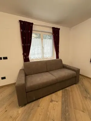 a couch in a living room with a window at Chalet La Viola in Alba di Canazei