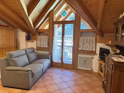 a living room with a couch and a large window at Appartamento Pelenzana in Predazzo
