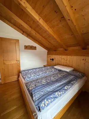 a bed in a room with a wooden ceiling at Appartamento Pelenzana in Predazzo