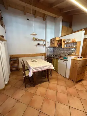 a kitchen with a table and a table and chairs at Appartamento Pelenzana in Predazzo