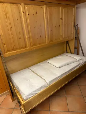 a bunk bed in a room with wooden cabinets at Appartamento Pelenzana in Predazzo