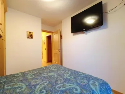 a bedroom with a bed with a television on the wall at Apartment Appartamento Ghezzi by Interhome in Campitello