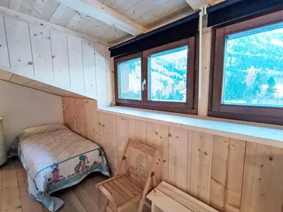 a bedroom with a bed in a room with wooden walls at Apartment Genziana-5 by Interhome in Penia