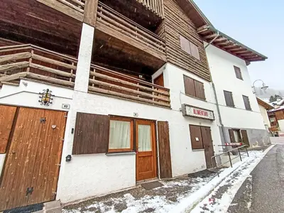 a building with wooden doors in the snow at Apartment Appartamento Matilde by Interhome in Penia