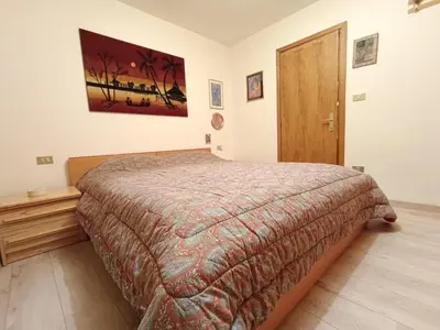 a bedroom with a bed and a wooden door at Apartment Appartamento Matilde by Interhome in Penia