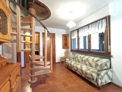 a living room with a couch and a spiral staircase at Apartment Des Alpes-19 by Interhome in Campitello di Fassa