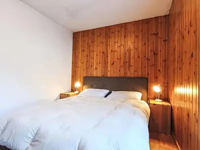 a bedroom with a white bed with wooden walls at Apartment Nuccia Navalge by Interhome in Moena