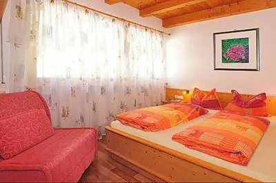a bedroom with a bed and a red couch at Apartment Walder in Fiumes