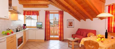 a kitchen and living room with a red couch and a table at Apartment Walder in Fiumes