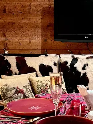 a table with a plate and a wine glass on a couch at Ciasa de Len Cortina in Cortina dʼAmpezzo