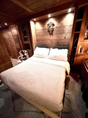 a bedroom with a large bed with a wooden wall at Ciasa de Len Cortina in Cortina dʼAmpezzo