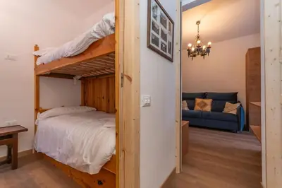 a bedroom with a bunk bed and a couch at El Mugo-Boscoverde 1 in Sottoguda