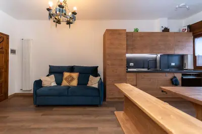 a living room with a blue couch and a kitchen at El Mugo-Boscoverde 1 in Sottoguda
