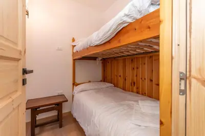 a bedroom with two bunk beds and a table at El Mugo-Boscoverde 1 in Sottoguda