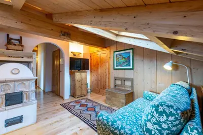 a living room with a blue couch and a fireplace at Cesa Lalla in Campitello di Fassa