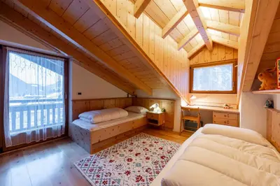 a attic bedroom with two beds and a large window at Cesa Lalla in Campitello di Fassa