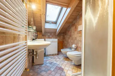 a bathroom with two sinks and a toilet and a window at Cesa Lalla in Campitello di Fassa