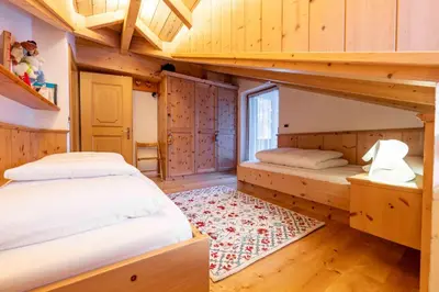 two beds in a room with wooden walls at Cesa Lalla in Campitello di Fassa