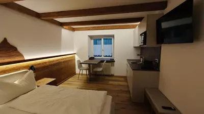 a bedroom with a bed and a desk and a kitchen at Il Laricino in Predazzo