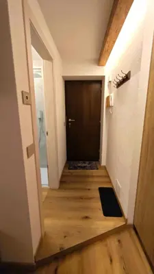 a hallway with a black door and a wooden floor at Il Laricino in Predazzo