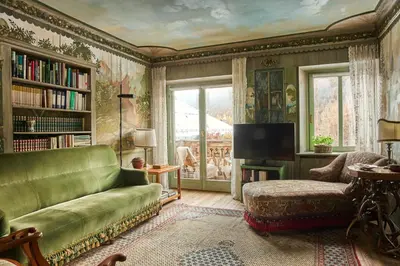 a living room with a green couch and a tv at Dimora Nobile d'Ottocento - parcheggio interno in Cortina dʼAmpezzo