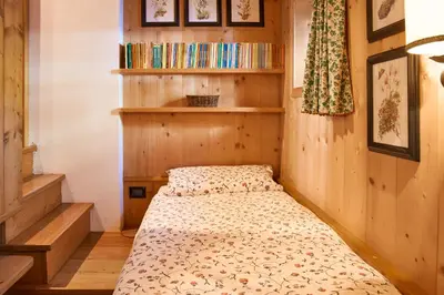 a bed in a room with wooden walls and shelves at Dimora Nobile d'Ottocento - parcheggio interno in Cortina dʼAmpezzo