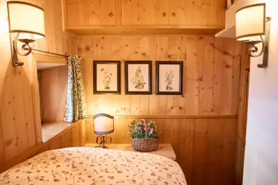a bedroom with wooden walls and a bed with two lamps at Dimora Nobile d'Ottocento - parcheggio interno in Cortina dʼAmpezzo
