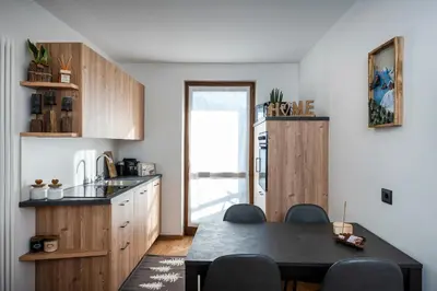 a kitchen with wooden cabinets and a table with chairs at Happiness 14 in Castello di Fiemme