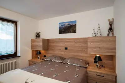 a bedroom with a large bed with a wooden headboard at Happiness 14 in Castello di Fiemme