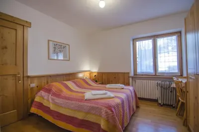 a bedroom with a bed with two towels on it at Cortina da vivere il tuo rifugio a due passi da tutto in Cortina dʼAmpezzo