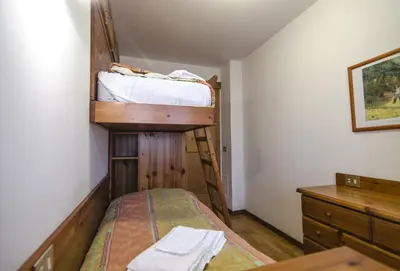 a bedroom with two bunk beds and a desk at Cortina da vivere il tuo rifugio a due passi da tutto in Cortina dʼAmpezzo
