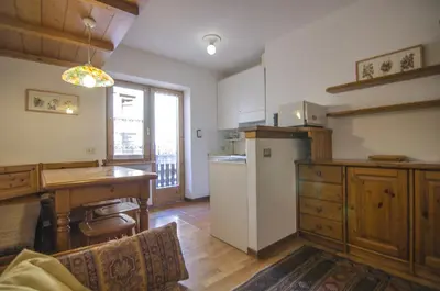 a kitchen with a refrigerator and a table and a counter at Cortina da vivere il tuo rifugio a due passi da tutto in Cortina dʼAmpezzo