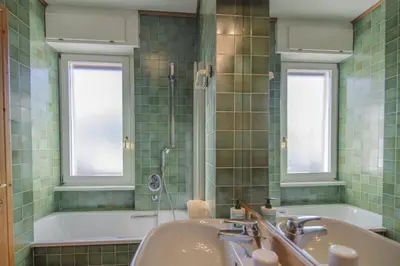 a green tiled bathroom with a tub and a sink at La tua coccola a Cortina in Cortina dʼAmpezzo