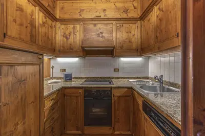 a kitchen with wooden cabinets and a black dishwasher at Casa Lana, comfort nel centro di Cortina d Ampezzo in Cortina dʼAmpezzo