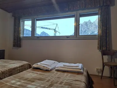a bedroom with two beds and a window with a crane at Luminoso e centralissimo attico, splendida vista panoramica sulle Dolomiti e sulle piste olimpiche in Cortina dʼAmpezzo