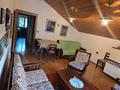 a living room with a couch and a table and chairs at Luminoso e centralissimo attico, splendida vista panoramica sulle Dolomiti e sulle piste olimpiche in Cortina dʼAmpezzo