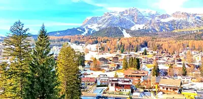 a town with a snowy mountain in the background at Luminoso e centralissimo attico, splendida vista panoramica sulle Dolomiti e sulle piste olimpiche in Cortina dʼAmpezzo