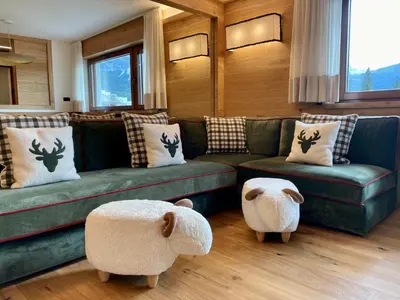 a living room with a green couch and two ottomans at Charming ground floor flat with breathtaking views in Cortina dʼAmpezzo