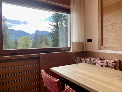a dining room with a table and a large window at Charming ground floor flat with breathtaking views in Cortina dʼAmpezzo
