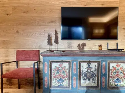 a blue cabinet with a red chair and a tv on a wall at Charming ground floor flat with breathtaking views in Cortina dʼAmpezzo