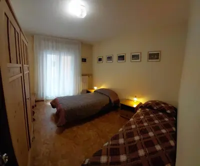 a bedroom with two beds and a window at Appartamento IN CENTRO a Predazzo in Predazzo